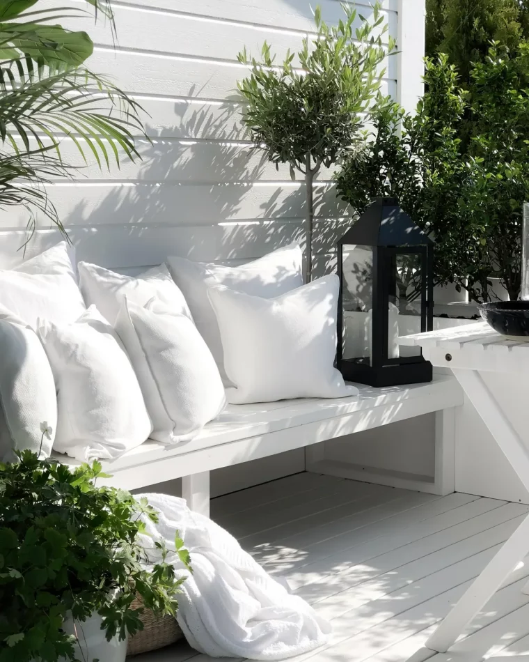 banc incastre blanc avec des coussins blancs plantes vertes