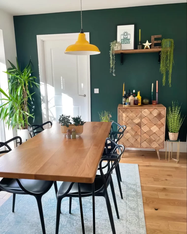 mur en vert sapin table et meuble en bois chaises noires