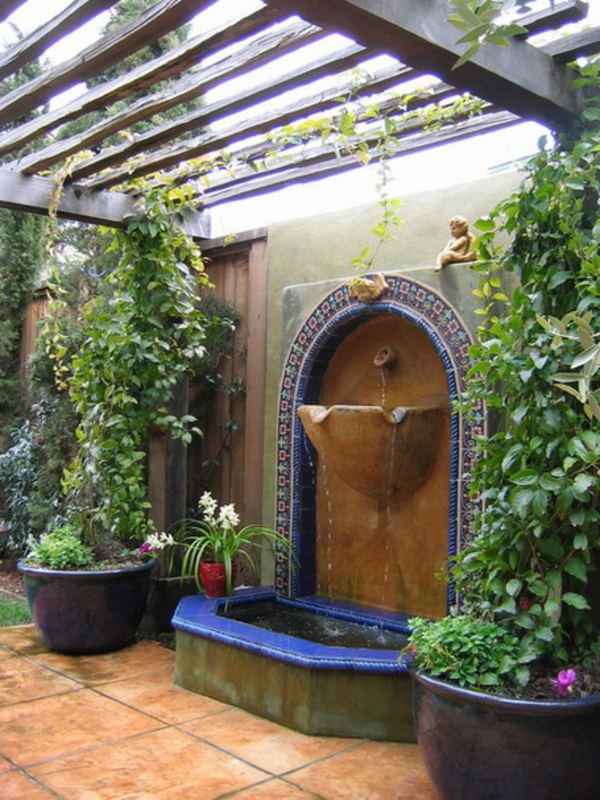 fontaine-murale-et-pots-de-fleurs-sous-un-pergola-en-bois