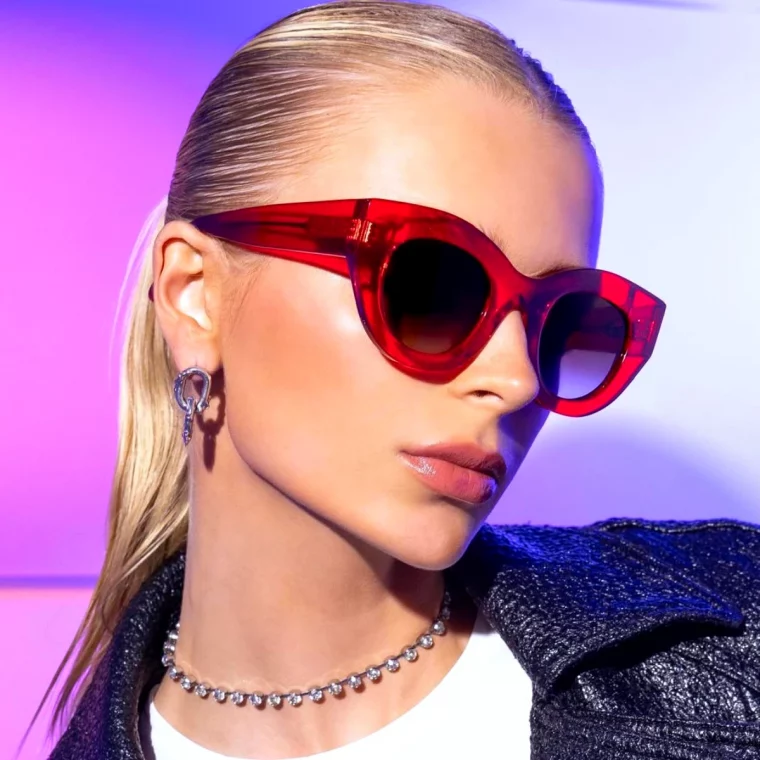 femme blonde cheveux attaches lunettes de soleil rouge