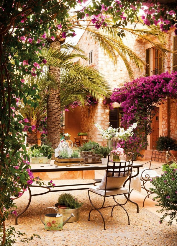 beau-jardin-avec-galets-décoratifs-fleurs-chaises-en-fer-forgé