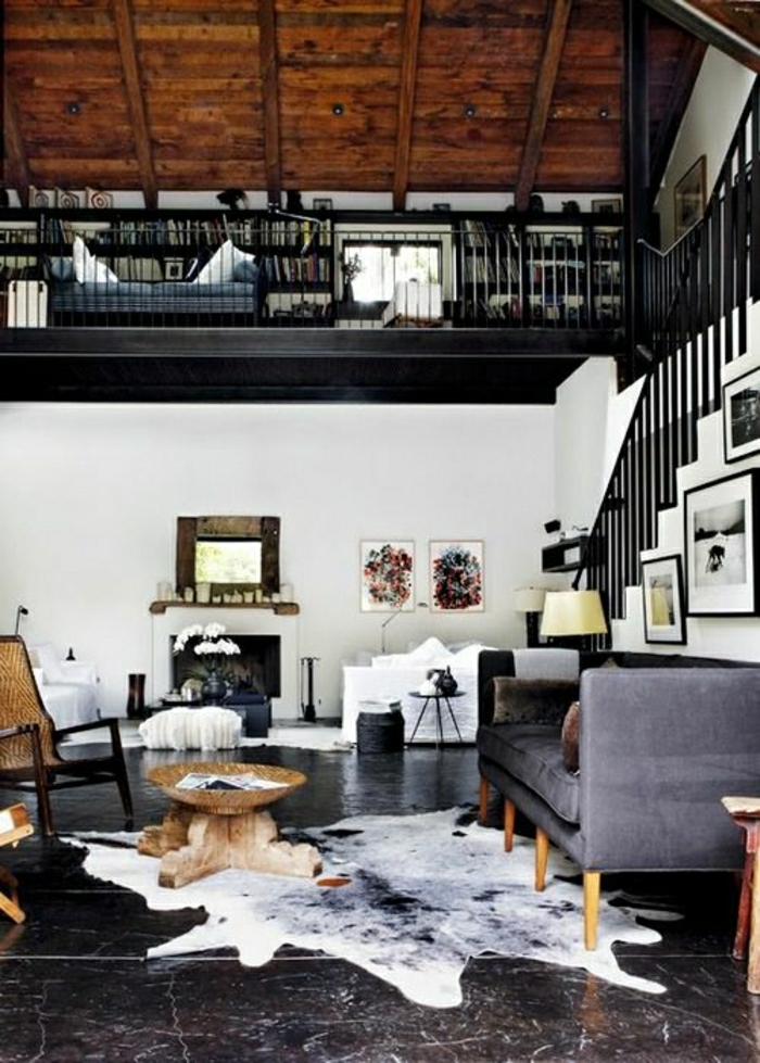 canapé-gris-tapis-en-cuir-carrelage-noir-plafond-haut-mansardé-carrelage-noir-petite-table-de-salon