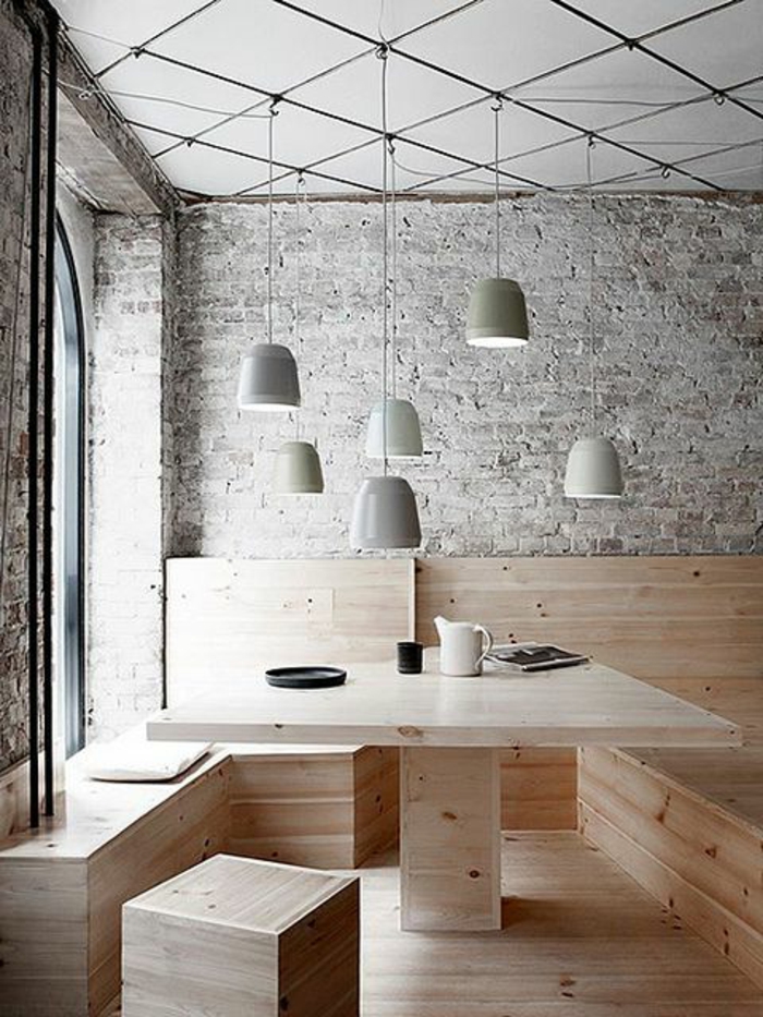 mur-en-brique-une-table-et-banquettes-en-bois-et-lampes-pendantes