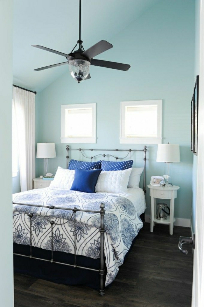 murs-bleus-coussins-colorés-lit-en-fer-forgé-table-de-nuit-en-bois-blanc