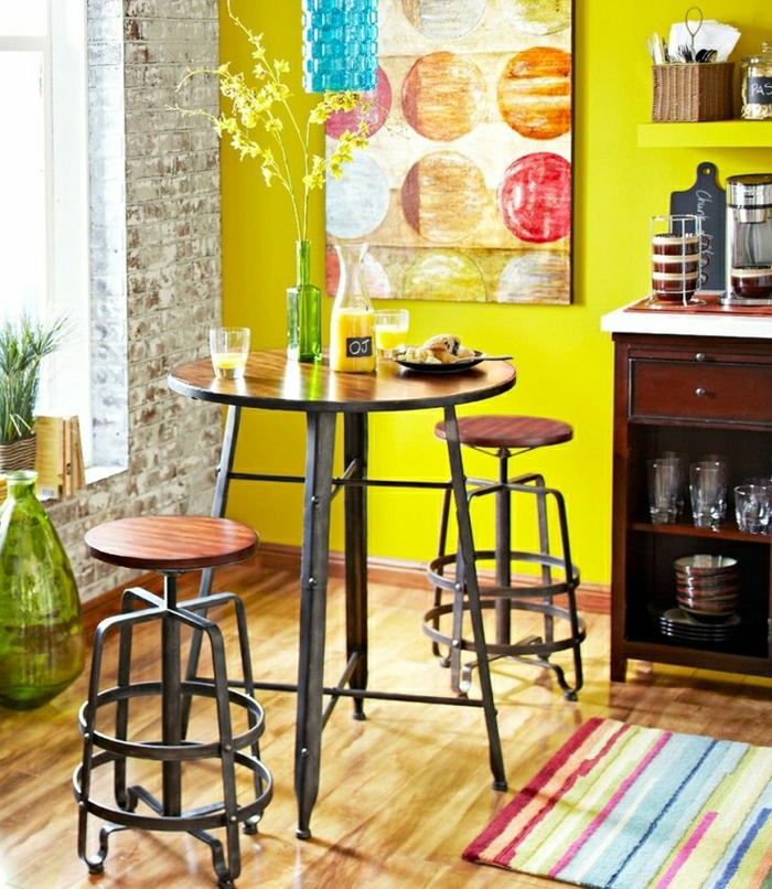 1-table-salle-a-manger-mur-jaune-mur-de-briques-fenetre-plein-de-lumière-tapis-coloré