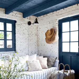 decoration marine plafond en bleu murs en briques blanches canape coussins chapeau en paille