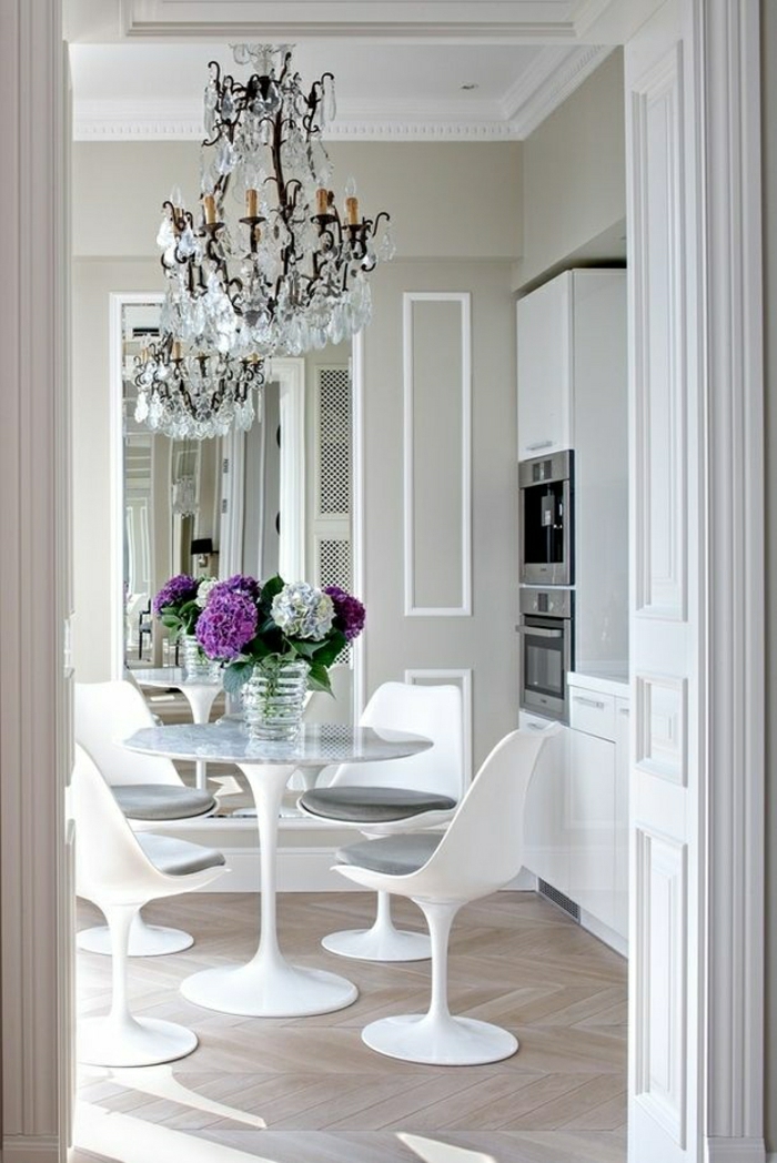 lustre-baroque-en-crystal-table-tulipe-en-plastique-blanc-sol-en-parquet-mur-chaises-blanches