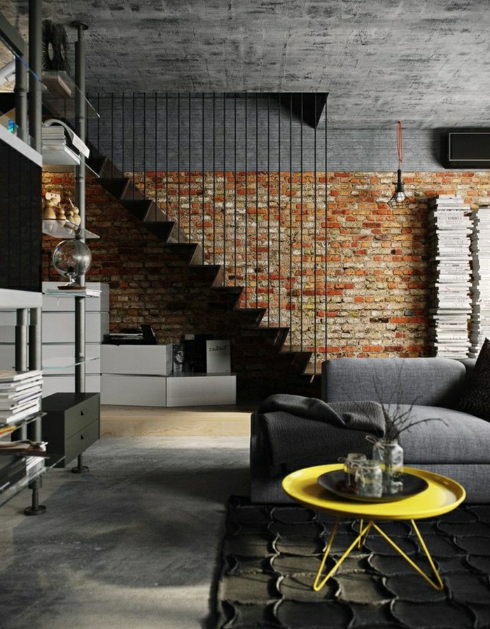 petite-table-basse-en-fer-jaune-sol-en-parquet-tapis-gris-canapé-noir-murs-de-briques