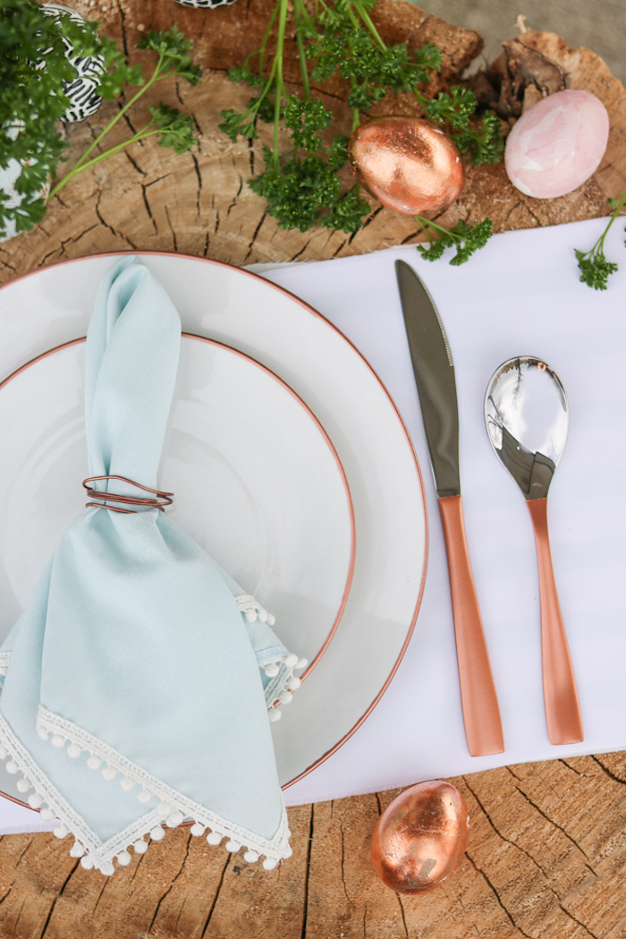 pliage de serviette de table en tissu bleu clair à festons avec rond de serviette cuivre, deco table style champetre chic