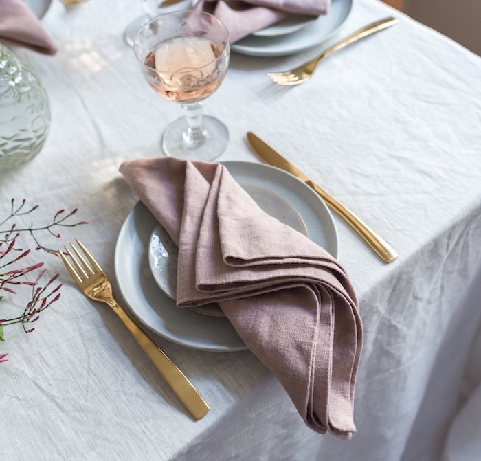 pliage serviette facile rose pale sur nappe blanche, couverts de table or, idee pliage de serviette facile 