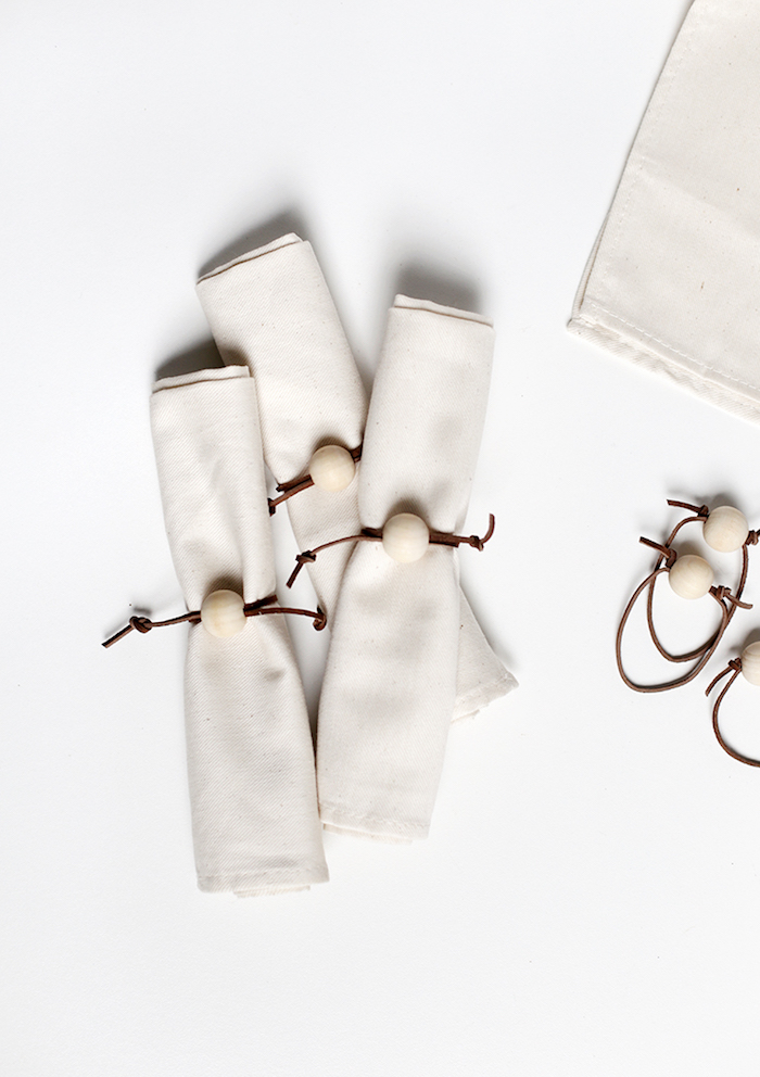 pliage serviette simple, serviettes blanches enroulées avec serre-serviette en bandes de cuir marron avec boule blanche