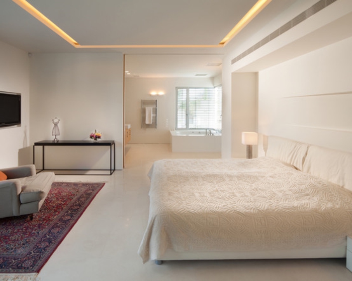 une-jolie-chambre-à-coucher-blanche-avec-tapis-coloré-murs-blancs-plafond-faux