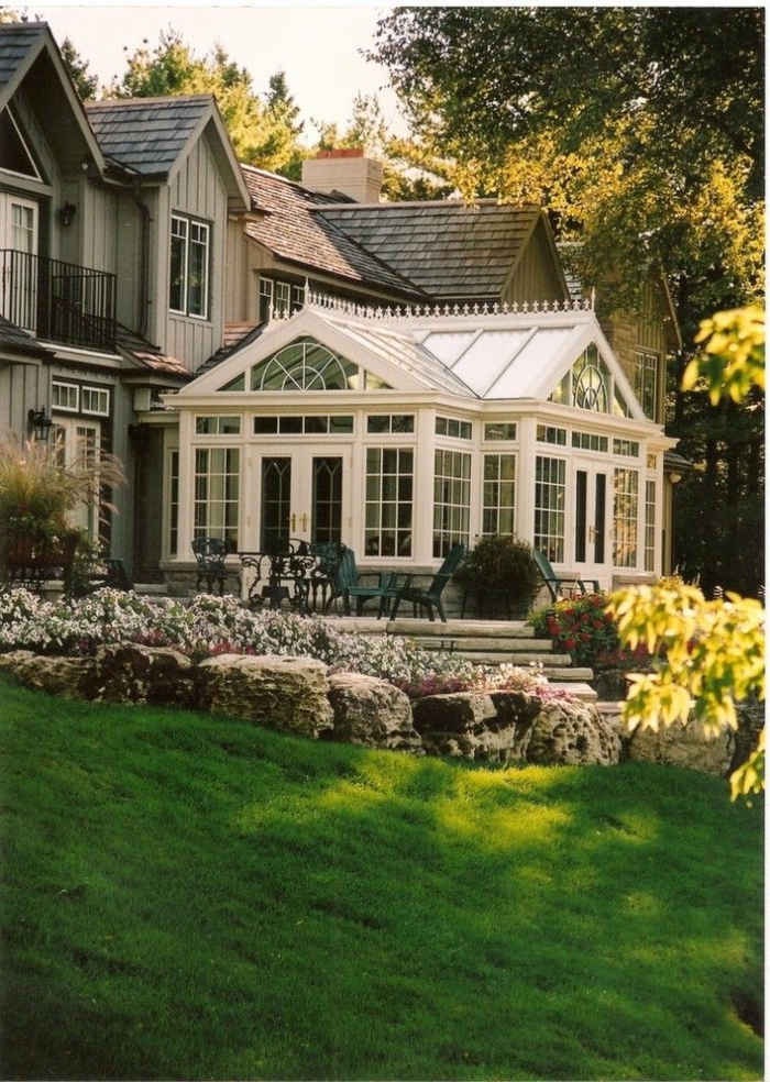 1-vérandas-en-kit-dans-le-jardin-avec-pelouse-verte-devant-la-maison-avec-mur-en-verre-et-plafond-sous-combles