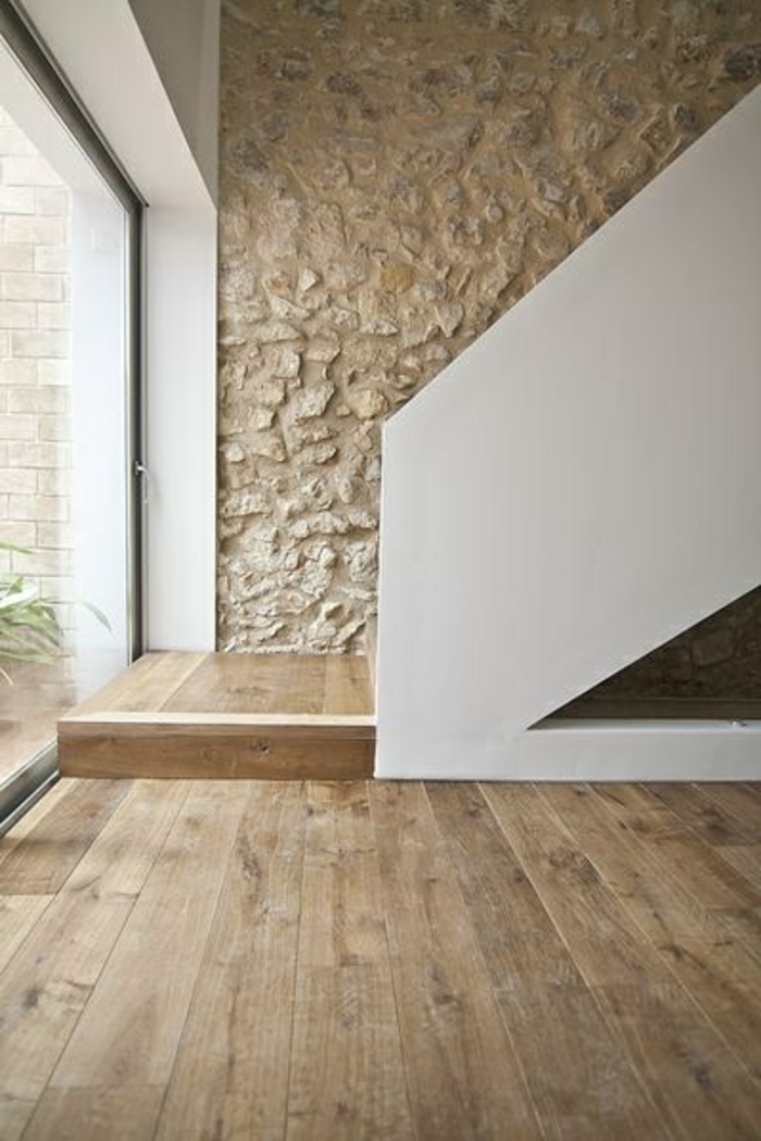 mur-en-pierre-apparente-dans-le-couloir-sol-en-planchers-clairs-et-escalier-d-interieur