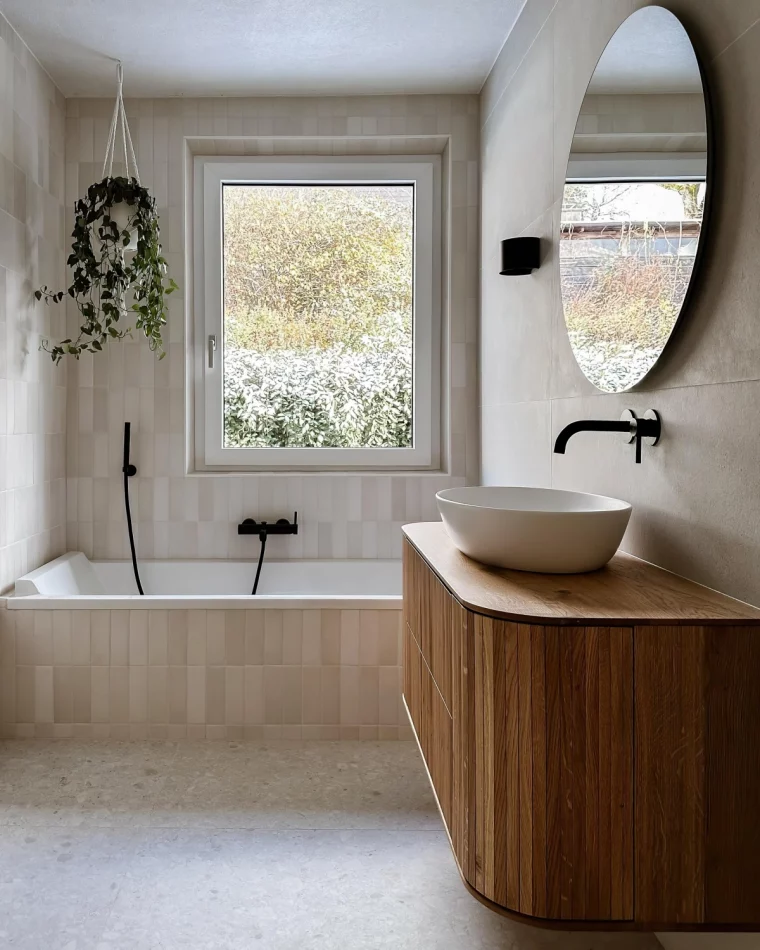petite salle de bain avec baignoire carrelage beige miroir rond meuble bois