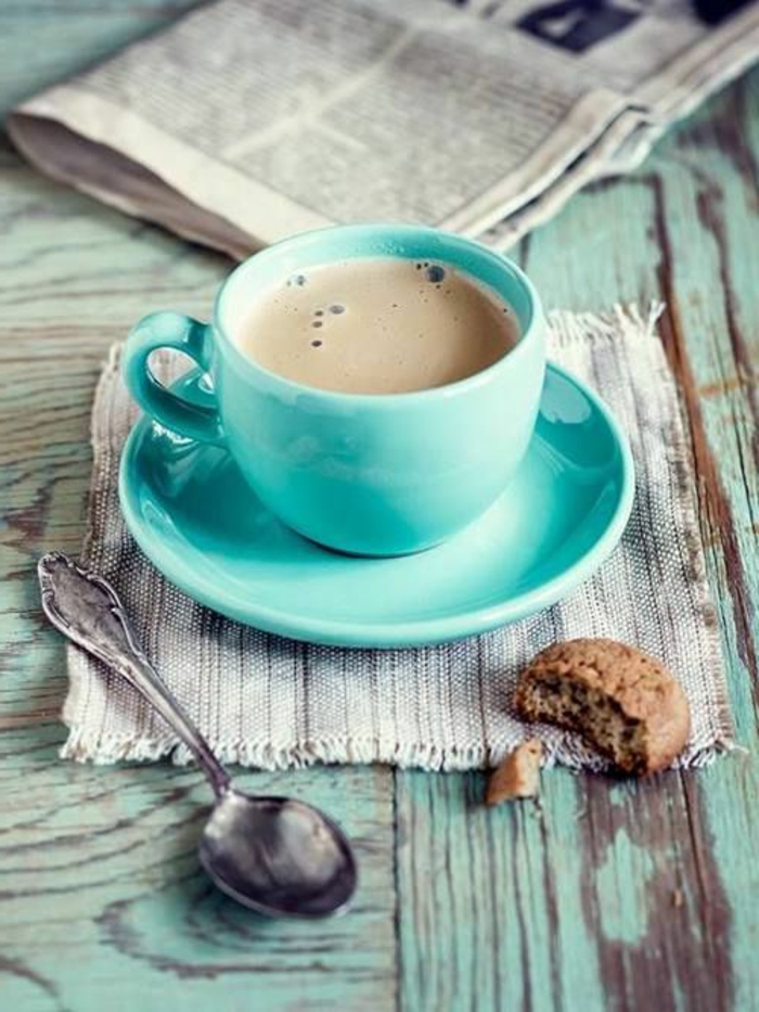 1-tasse-à-café-nespresso-bleu-clair-avec-biscuit-une-table-en-bois-massif-et-tasses-à-café-bodum
