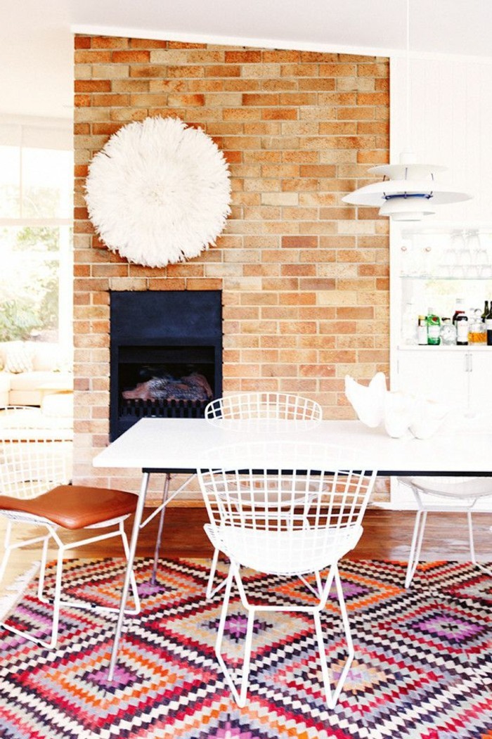 salon-moderne-avec-sol-en-parquet-tapis-coloré-mur-de-briques-tables-chaises-blances