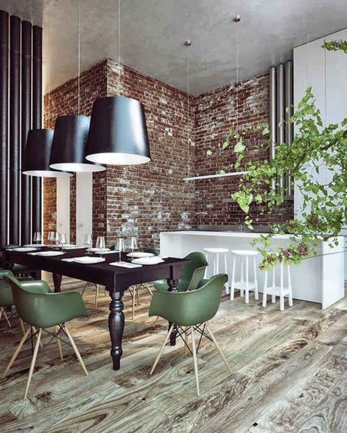 salle-à-manger-design-avec-murs-de-briques-rouges-sol-en-parquet-clair-chaise-de-table-vertes