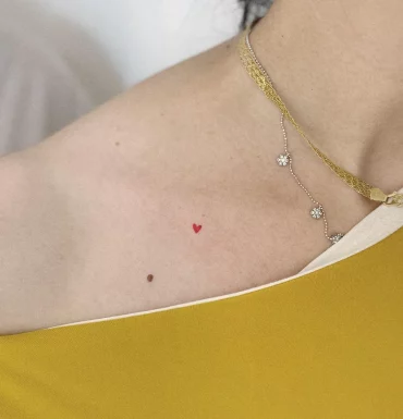 petit tatouage de coeur rouge miniscule collier or blouse jaune moutarde