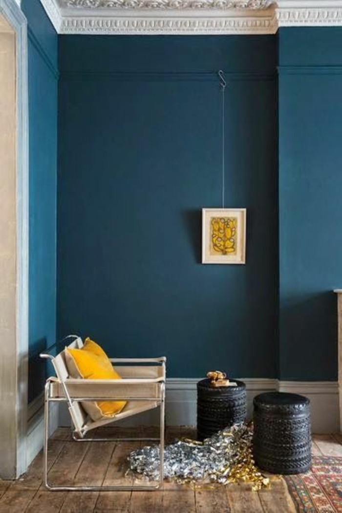 salon-murs-en-bleu-foncé-canape-beige-sol-en-planchers-bois-tapis-coloré-chaises-basses-en-rotin