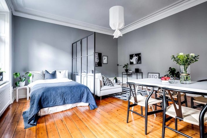 améangement petit appartement avec salle à manger, chambre avec linge de lit bleu et blanc, verrière de séparation à coté d un salon gris et blanc