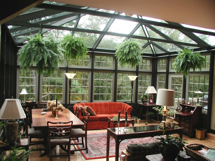 verrière-extérieure-noire-aménagée-avec-de-meubles-en-bois-un-joli-sofa-contrastante-végétation-qui-surplombe-le-décor-vintage