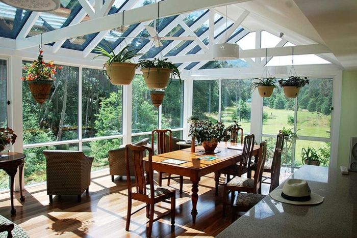 formidable-idee-deco-veranda-aménagée-en-salle-à-manger-une-abondance-de-plantes-sol-stratifié-vue-sur-un-paysage-forestier