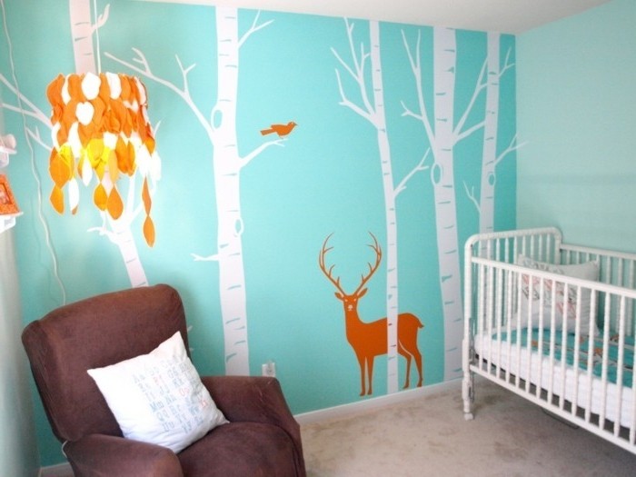 peinture-chambre-bébé-à-jolis-motifs-sur-un-fond-bleu-canapé-marron-lit-à-barreaux-blanc
