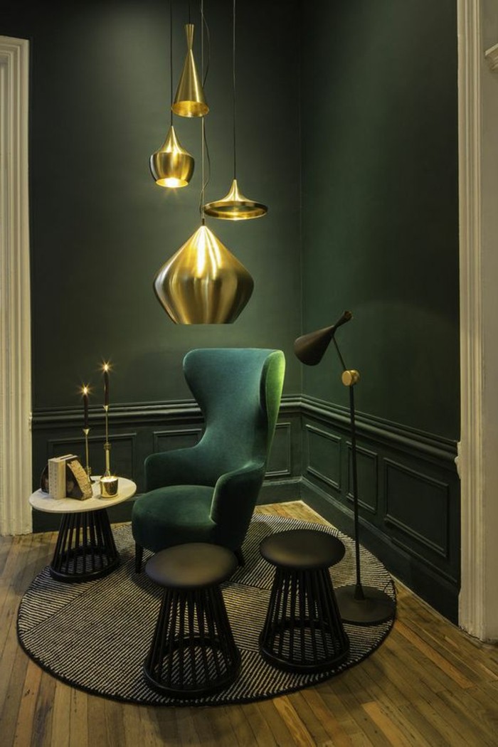 lampe-en-or-tapis-rond-chaise-en-bleu-foncé-sol-en-parquet-mur-vert-eclairage-intérieur