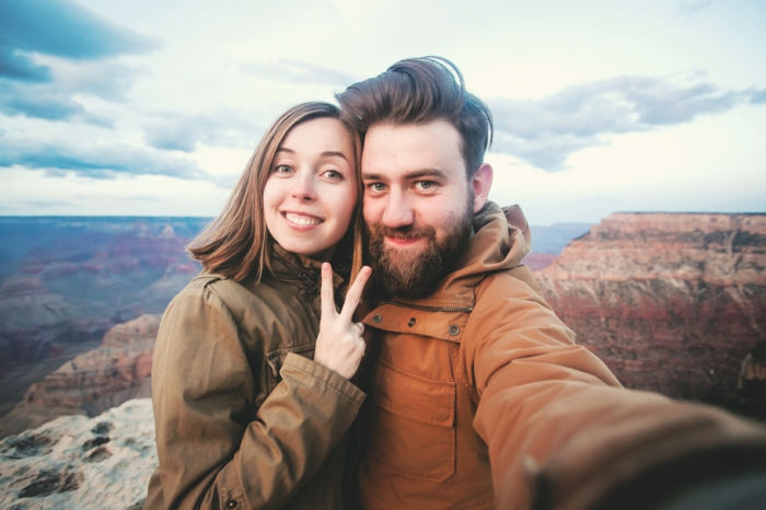 Romantic couple or friends show thumbs up and make selfie photo on travel hiking at Grand Canyon viewpoint in Arizona, USA