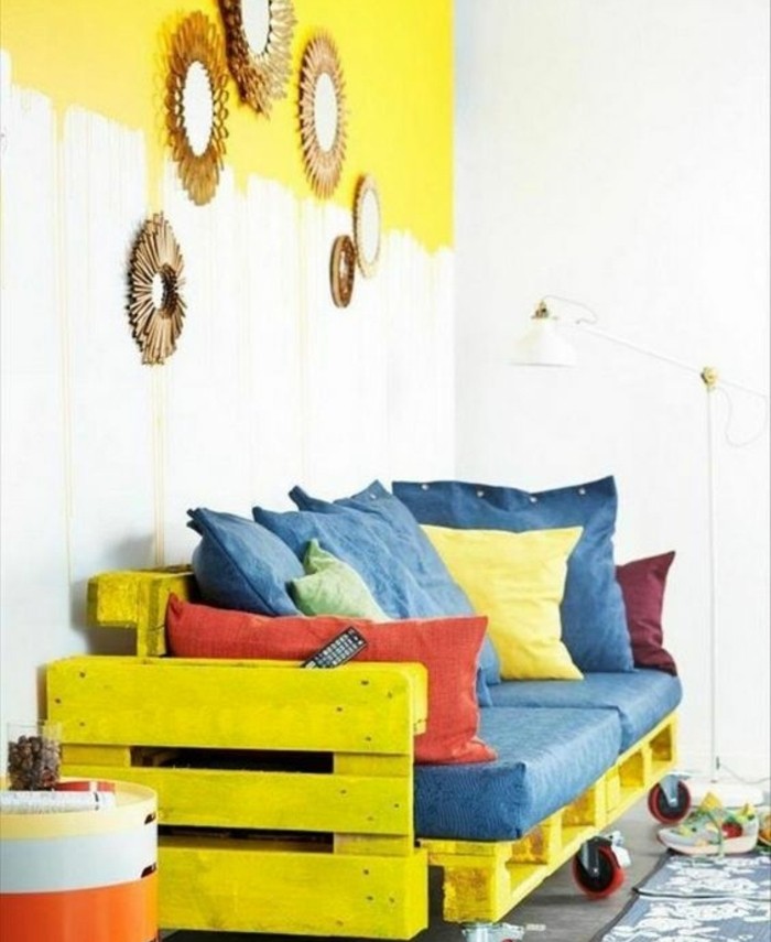 comment-fabriquer-un-canape-en-palette-superbe-idee-canape-a-rouolettes-jaune-assises-bleues-coussins-de-differentes-couleurs