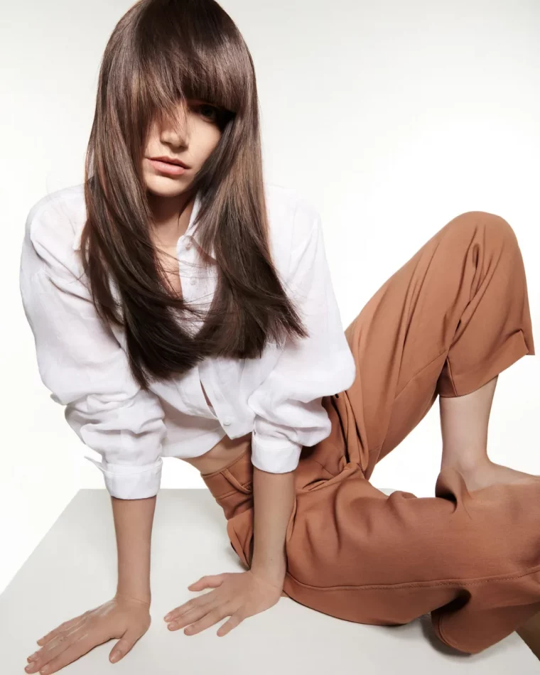 femme en chemisier blanc pantalon caramel cheveux longs avec frange