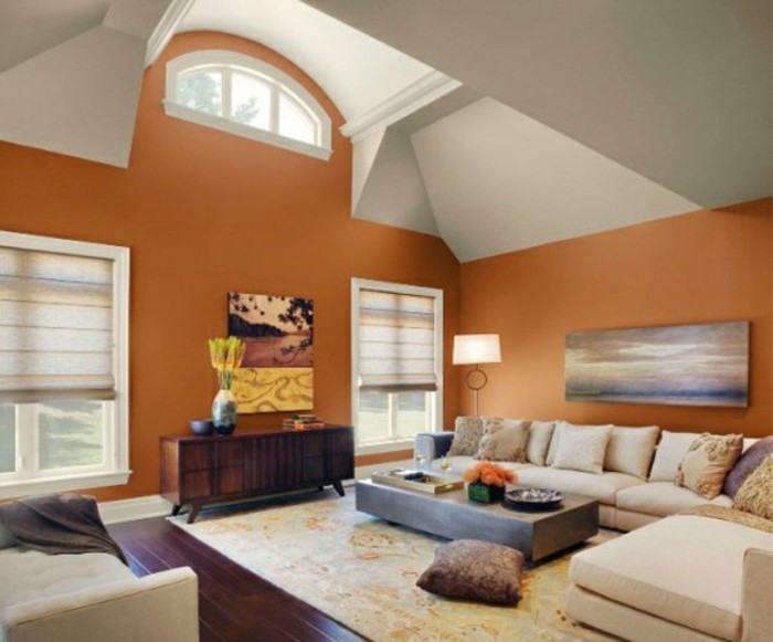 grand-salon-sous-pente-mur-en-orange-tapis-colore-sol-en-parquet-fonce