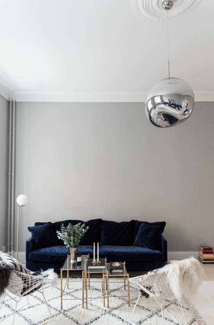 tapis-blanc-noir-canape-bleu-fonce-table-en-verre-et-metal-lustre-boule-mur-gris