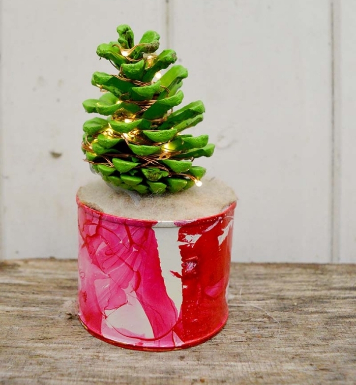 idée bricolage noel facile, modèle de mini sapin fait main en pomme de pin peinte en vert décoré de guirlande lumineuse