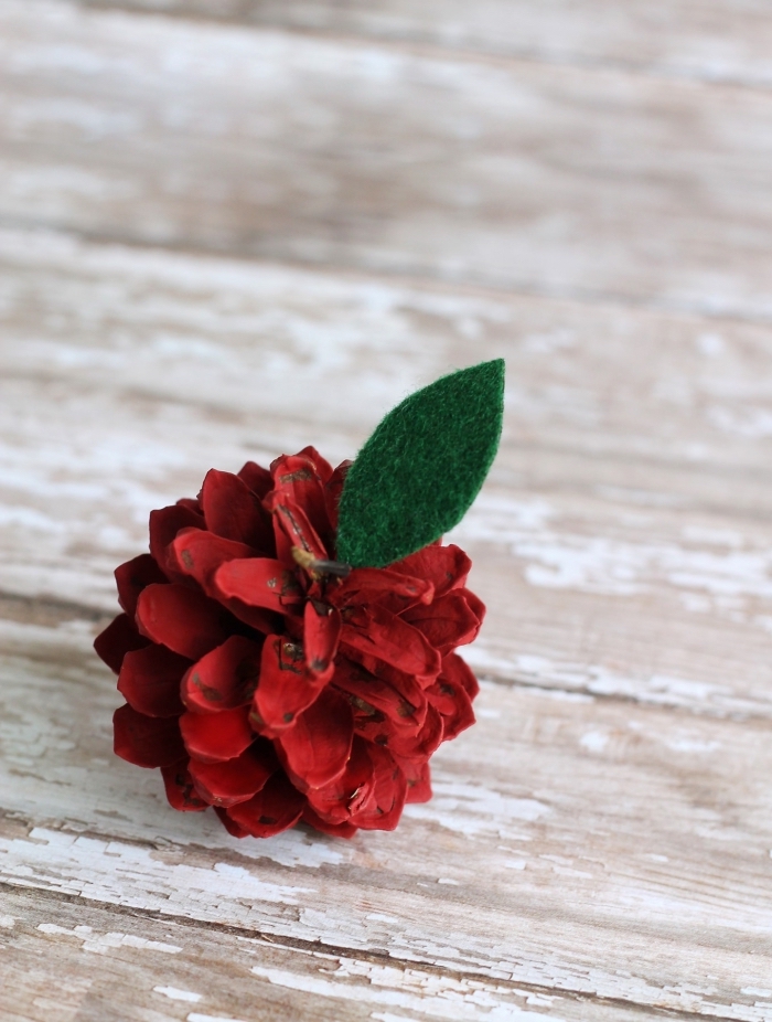 fabriquer un objet décoration noel en pommes de pin peint en rouge avec feuille en feutrine, diy fruit en pomme de pin