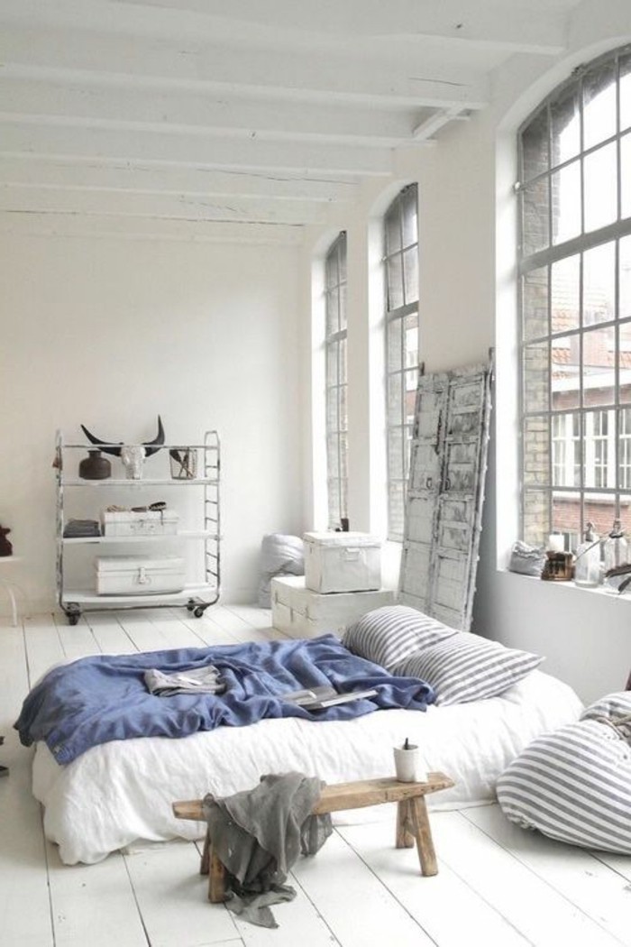linge-de-lit-blanc-couverture-de-lit-bleu-fonce-sol-en-planchers-blancs-murs-blancs