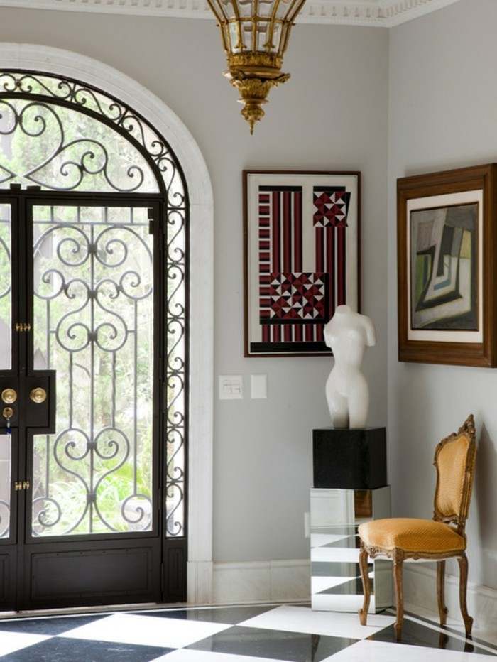 porte-en-fer-forge-lustre-en-or-peinture-art-contemporain-statuette-chaise-en-bois-plafond-en-platre