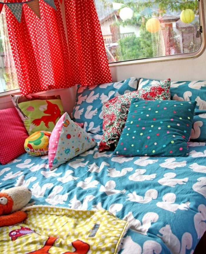 camion-caravane-lit-enfant-couverture-de-lit-bleu-avec-des-coussins-colorés