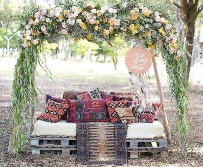 canapé-en-palette-décoré-de-coussins-style-oriental-sous-un-autel-fleuri-decoration-palettes-mariage-boheme-chic