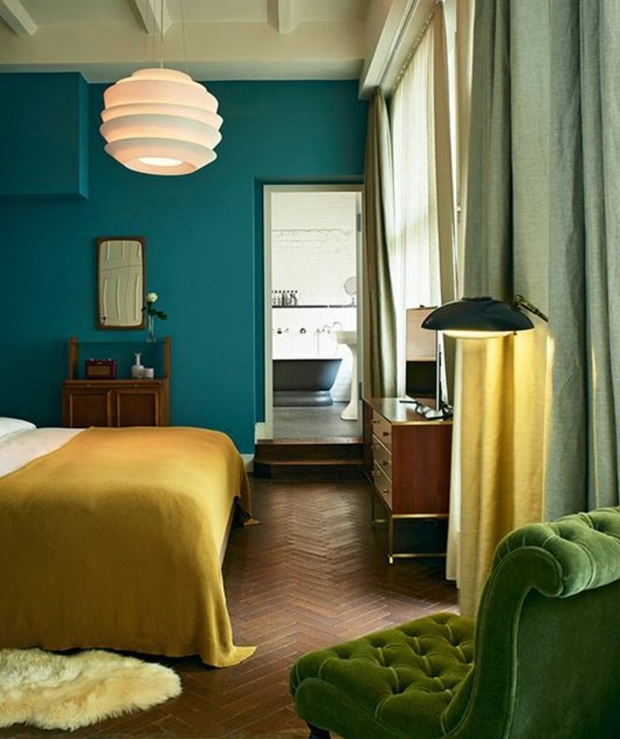 chambre-couleur-bleu-petrole-canape-et-rideaux-verts-couverture-de-lit-jaune-parquet-marron-mobilier-bois-marron-vintage