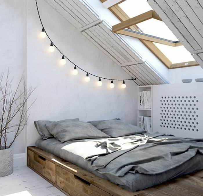 decoration-scandinave-pour-amenager-une-mansarde-en-chambre-a-coucher-lit-en-bois-avec-rangements-matelas-apparent-une-guirlande-d-ampoules-electriques