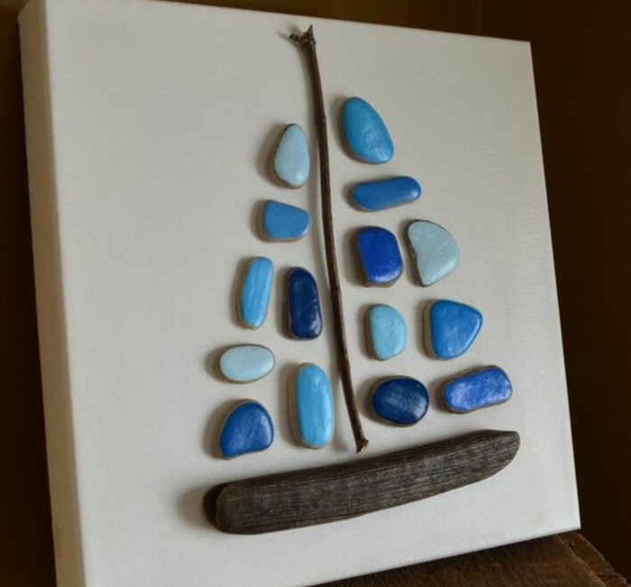galets-peints-en-bleu-et-de-petits-morceaux-de-bois-arrangés-pour-figurer-un-bateau-idee-d-activité-manuelle-maternelle