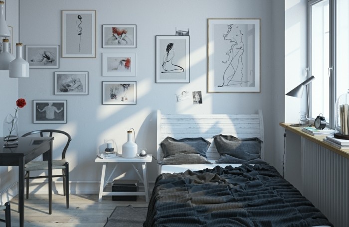 un-lit-minialiste-avec-une-tete-de-lit-en-bois-use-couverture-oreillers-grises-tables-et-chaises-couleur-grise-et-plusieurs-tableaux-graphiques