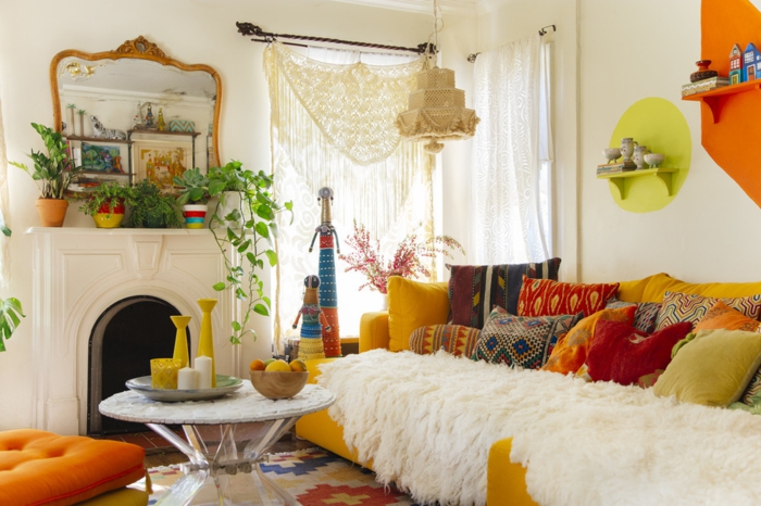 déco salon cocooning, table ronde, canapé jaune moutarde, miroir en cadre doré, coussins à motifs ethniques