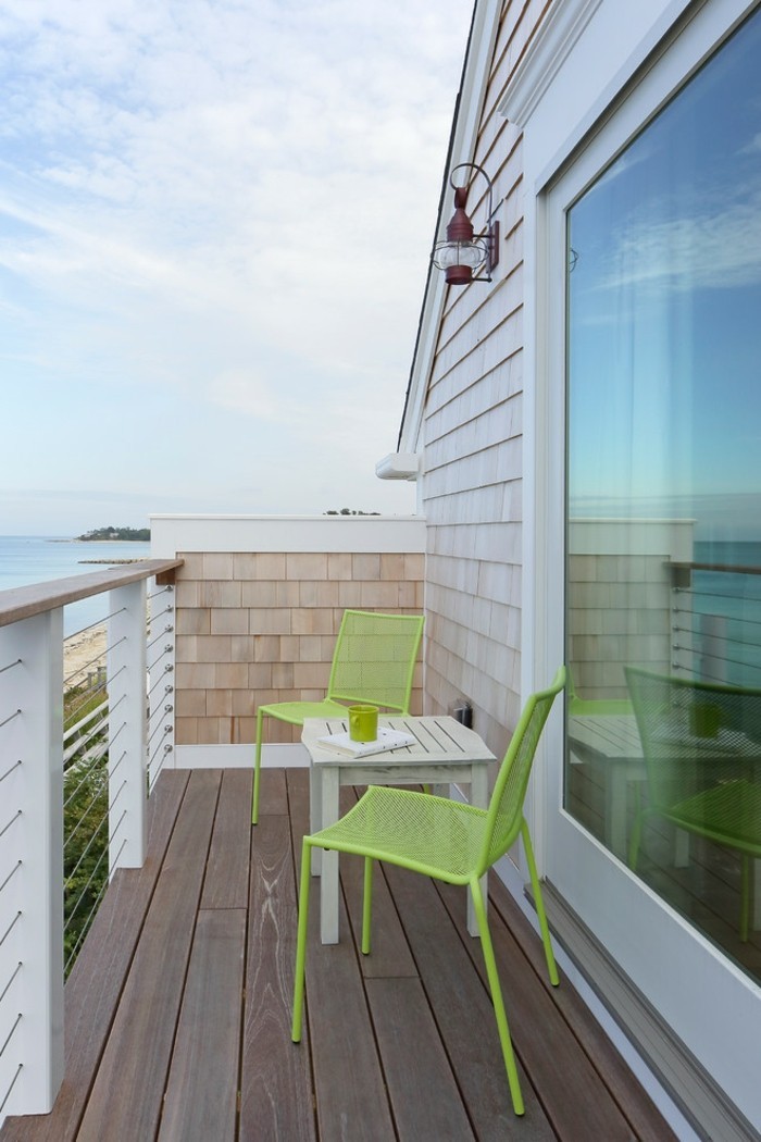 decoration balcon, vue sur la mer, table blanche en bois, chaises vertes