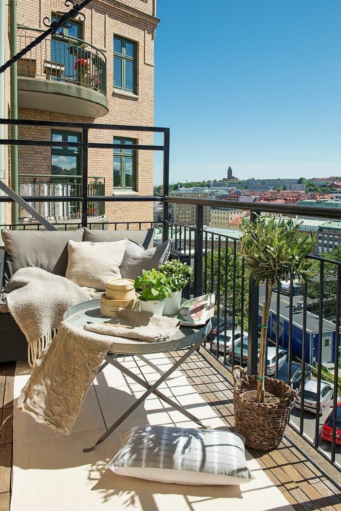 deco balcon, petit canapé noir, couverture beige à franges, table ronde pliante