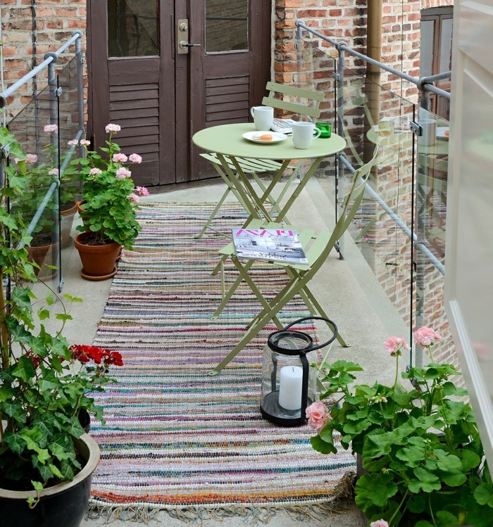 idee deco terrasse, tapis vieux multicolore, plantes vertes, porte marron, table ronde en vert