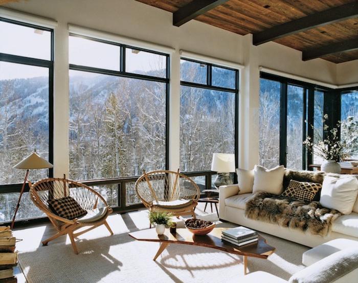 tapis cocooning, grandes fenêtres, plafond avec poutres en bois, chaises rondes, canapé blanc, coussins décoratifs