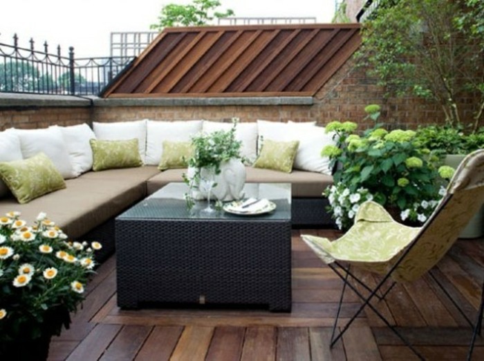 terrasse bois composite, table noire, chaise pliante, canapé d angle, coussins blancs et verts, plantes, exemple de terrasse tropezienne